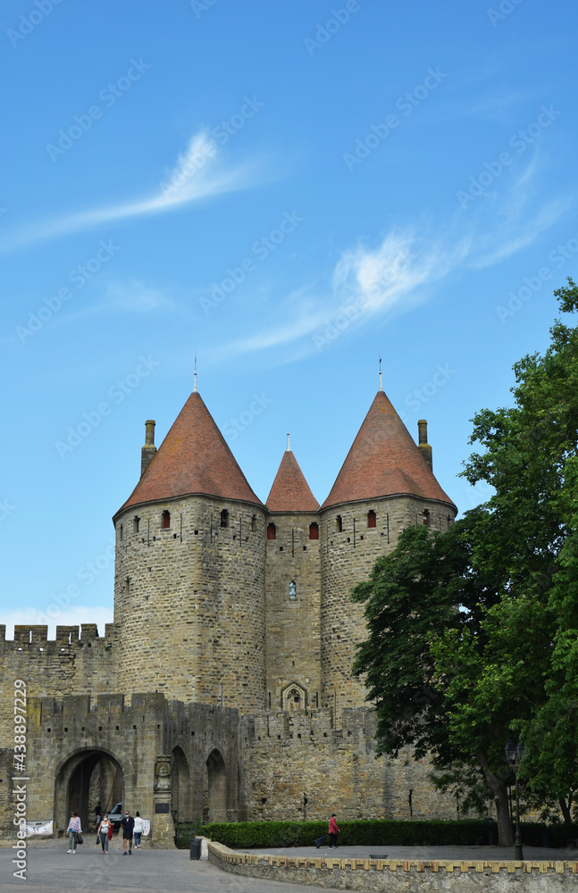 Cité médiévale de Carcassonne, la porte Narbonnaise sous un ciel bleu orné de fins filaments de nuages blancs.