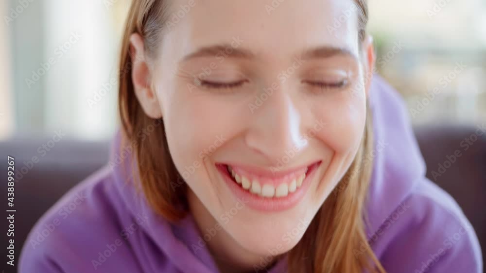 Closeup face of beautiful young woman with blue eyes looking at camera with serious facial expression and laughing cheerfully. Model having fun posing with her hands on chin Closeup face of beautiful young woman with blue eyes looking at camera with serious facial expression and laughing cheerfully. Model having fun posing with her hands on chin