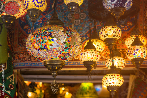 Middle Eastern lambas of different colors and sizes are hanging in the bazaar. Bright traditional Arabic and Turkish lanterns made of metal and glass, inlaid with mosaic details of different colors. © Zhanna