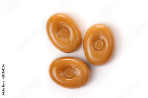 Three caramel candies on a white background close-up.