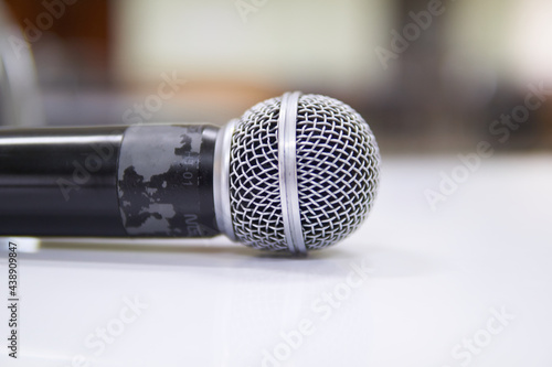 Hands holding a microphone in a conference room. 