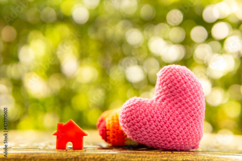 Hand are hold rainbow heart and home model.Give love to the family for happiness..Have background in garden and light of sun.