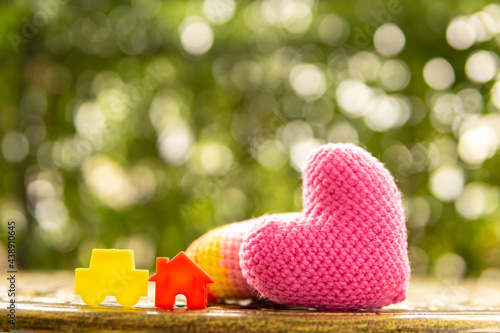 Hand are hold rainbow heart and home model.Give love to the family for happiness..Have background in garden and light of sun.