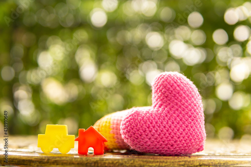 Hand are hold rainbow heart and home model.Give love to the family for happiness..Have background in garden and light of sun.