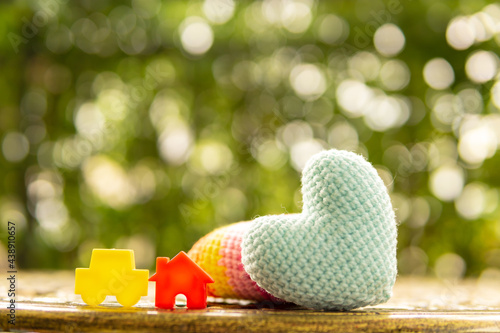 Hand are hold rainbow heart and home model.Give love to the family for happiness..Have background in garden and light of sun.