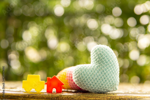 Hand are hold rainbow heart and home model.Give love to the family for happiness..Have background in garden and light of sun.