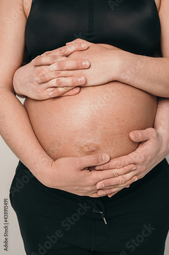 The belly of a pregnant girl is close-up. The husband is careful to hold the belly of the pregnant wife.