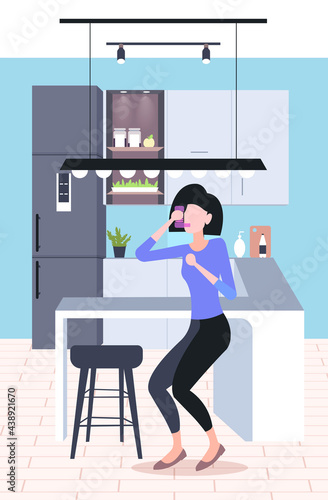 woman using spray inhaler to stop asthma attack symptoms affecting breath and lungs bronchial disease concept modern kitchen interior vertical full length