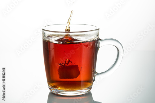 splash from falling piece of sugar in a transparent mug on a white background