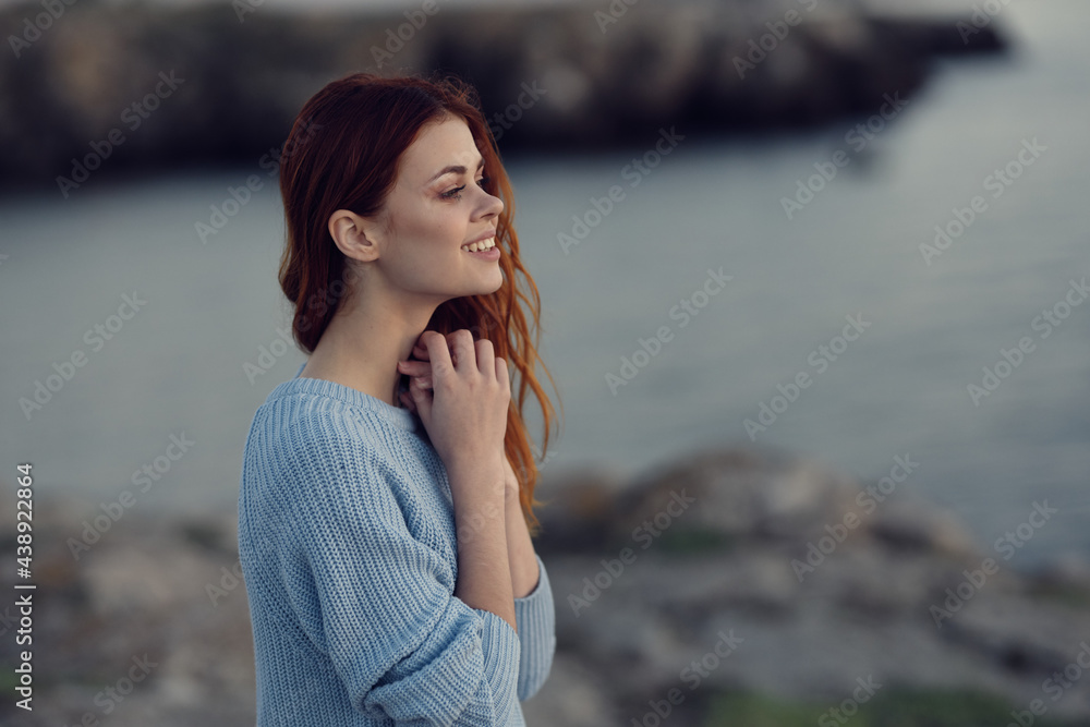 red-haired woman in a blue sweater near the river in nature red-haired woman in a blue sweater near the river in nature