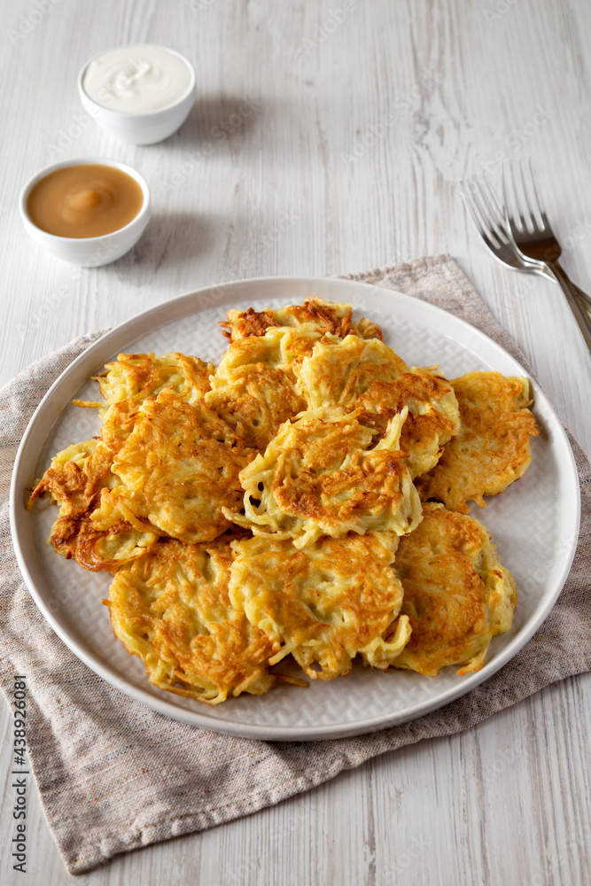 Homemade Potato Pancakes Latkes with Apple Sauce and Sour Cream on a white wooden background, side view. Homemade Potato Pancakes Latkes with Apple Sauce and Sour Cream on a white wooden background, side view.