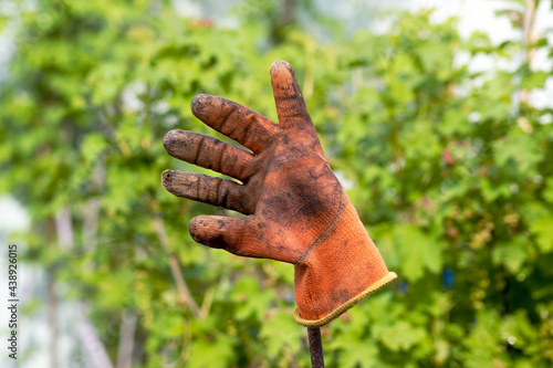 Dirty old glove on a metal bar. Gloves after cleaning the garden and vegetable garden.