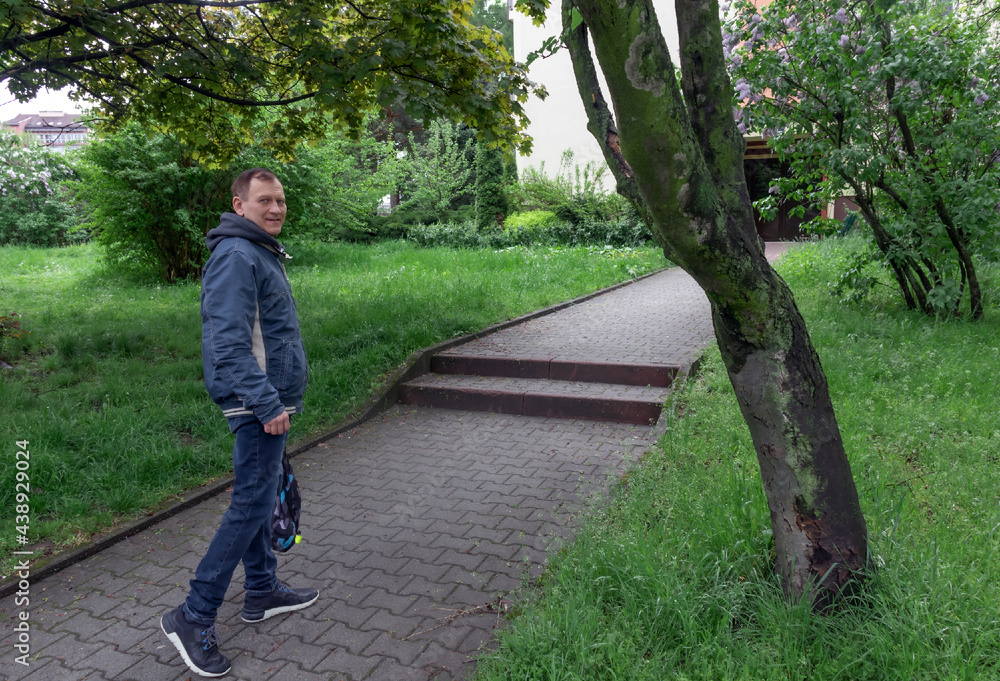 Obraz premium middle-aged man, 60 years old, walks along the footpath in the square and smiles