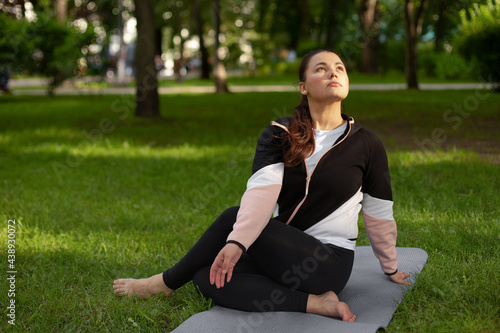 woman practices yoga in the park on green grass. pilates outdoor. the mental health concept