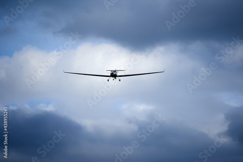 Small aircraft on landing approach. Dramatic sky with blue gray clouds. Front view.