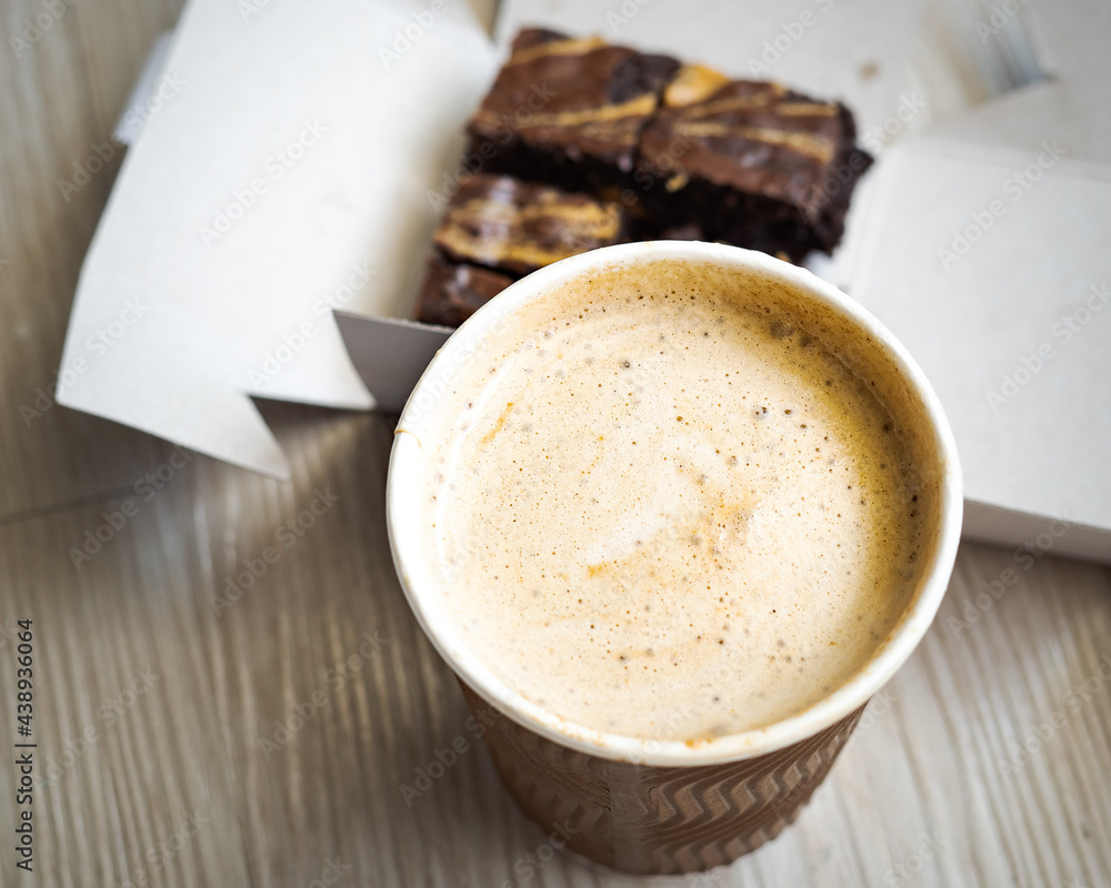 Top view of takeaway paper cup mix hot cappucino coffee foam served with freshly baked brownies. Top view of takeaway paper cup mix hot cappucino coffee foam served with freshly baked brownies.
