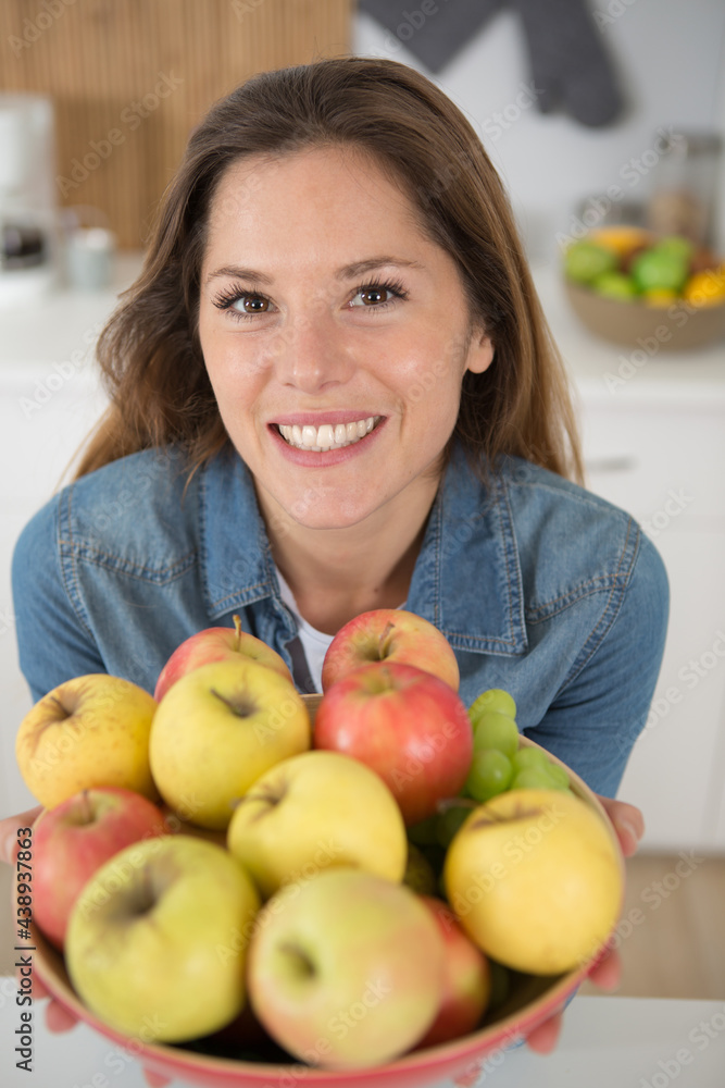 happy woman with green apples on a plate on kitchen happy woman with green apples on a plate on kitchen