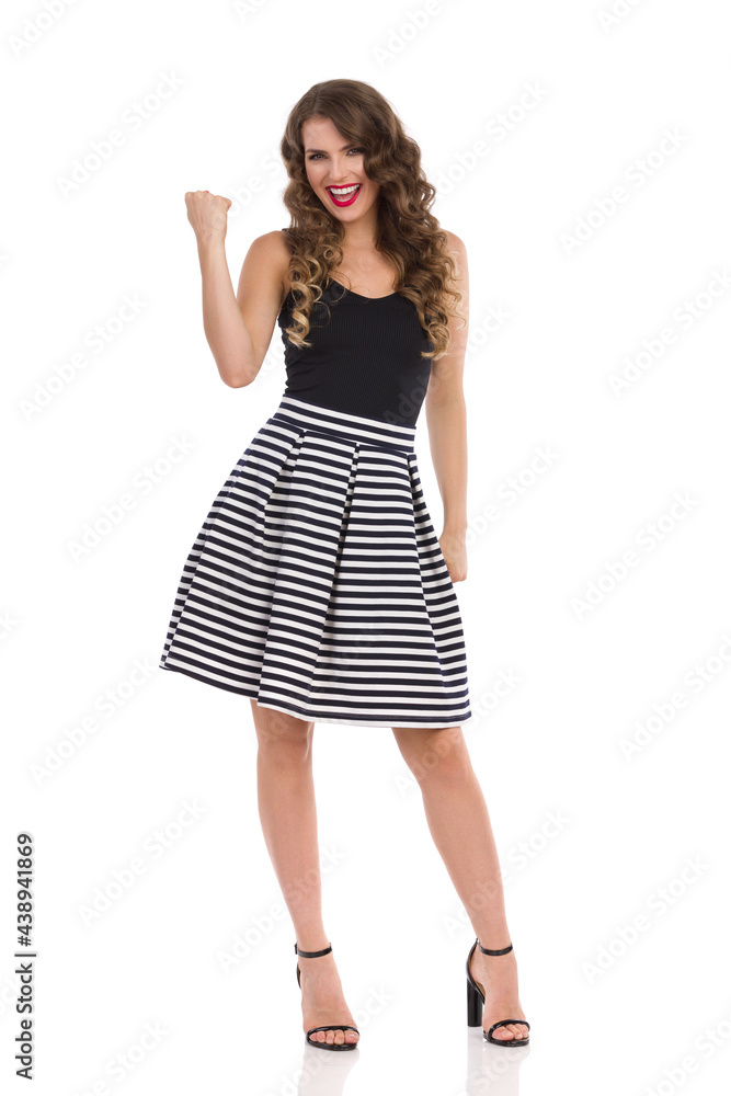 Fototapeta premium Confident Young Woman In Mini Skirt And High Heels Is Showing Fist And Laughing