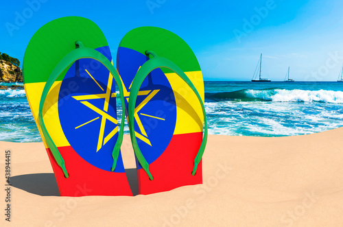 Flip flops with Ethiopian flag on the beach. Ethiopia resorts, vacation, tours, travel packages concept. 3D rendering