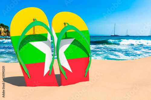 Flip flops with Myanmar flag on the beach. Myanmar resorts, vacation, tours, travel packages concept. 3D rendering