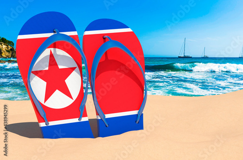 Flip flops with North Korean flag on the beach. North Korea resorts, vacation, tours, travel packages concept. 3D rendering