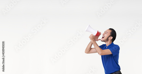 Happy young Asian man in blue shirt shouting announce into megaphone isolated on white background in studio.