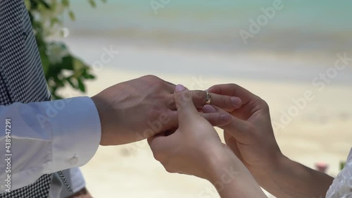 Exchanging wedding rings bride wearing for goom  sea and sky beach background. photo