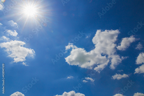 Sunbeams in summer with  white clouds on a blue sky background