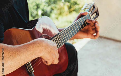 Hands of young guitarist, playing a melody on a Spanish acoustic guitar.