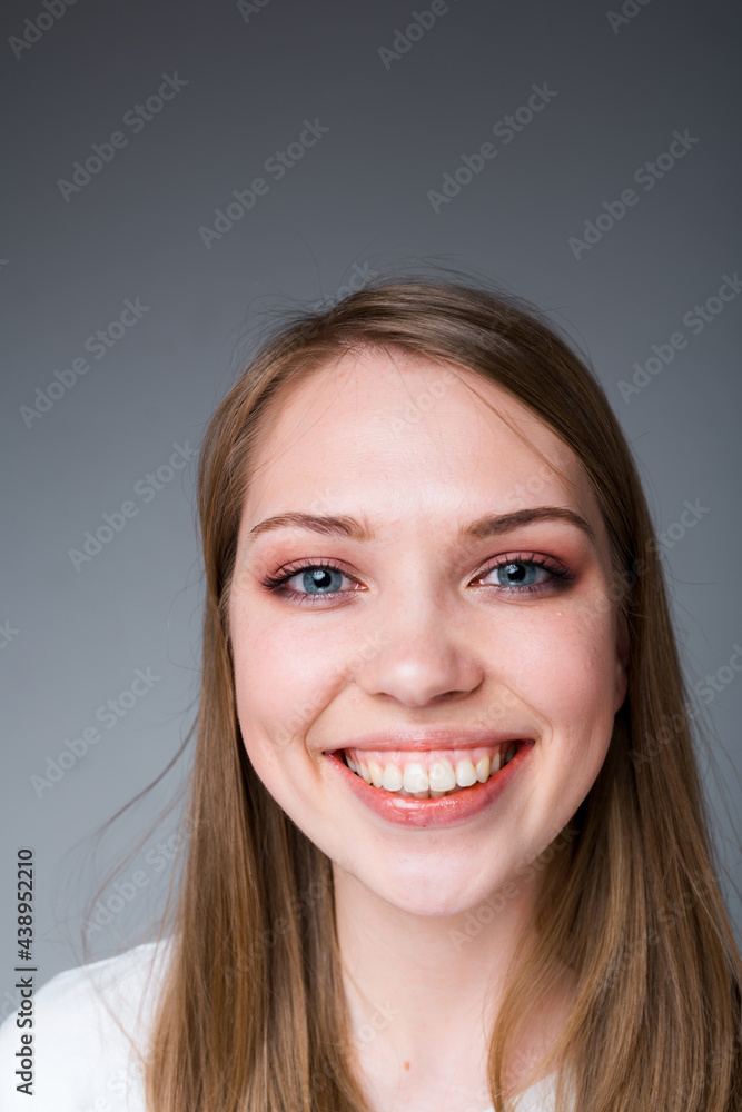 Happy girl with long hair smiling broadly showing snow-white teeth and looking at the camera Happy girl with long hair smiling broadly showing snow-white teeth and looking at the camera