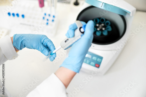 Tableau sur toile researcher using pipette and analysis flask samples into a centrifuge in laboratory