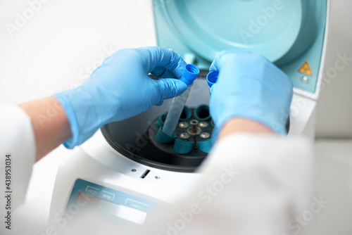 Tableau sur toile Female's hand in blue glove putting analysis samples into a centrifuge in laboratory