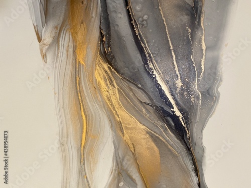 Abstract grey art with gold — black and white background with beautiful smudges and stains made with alcohol ink and golden paint. Grey fluid texture resembles marble, smoke, watercolor or aquarelle. © Luvricon