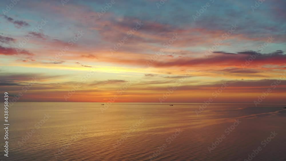 Aerial shot flying into beautiful orange sunset sky over sea Aerial shot flying into beautiful orange sunset sky over sea