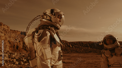 Male astronaut adjusting camera on colleague