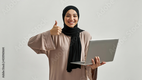 Young arabian woman in hijab showing thumb up photo