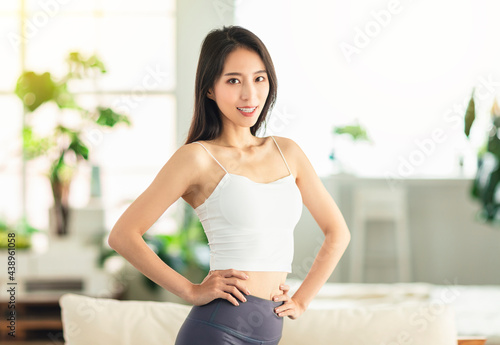 Free Download A young woman with her arms akimbo, ready to do fitness and exercise at home, and looks confidently - GFXLoad