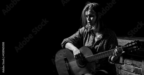 Woman playing guitar, holding an acoustic guitar in his hands. Music concept. Girl guitarist plays