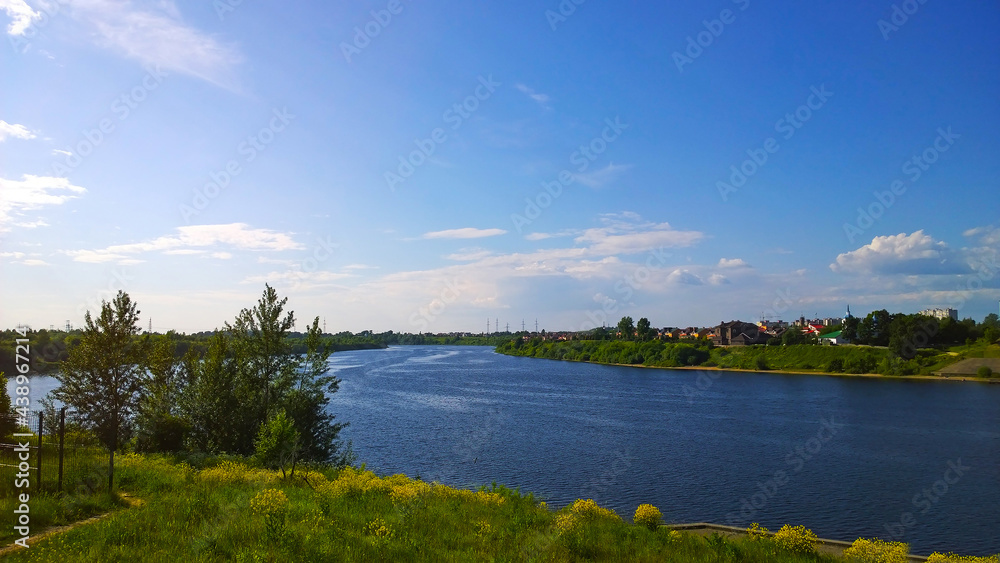Blue sky over Velikaya River, Pskov, Russia. Beauty in nature. Landscape. Clear calm water. Green grass shore. Ecology concept. Environment conservation. Rural scene. Warm sunny summer day.