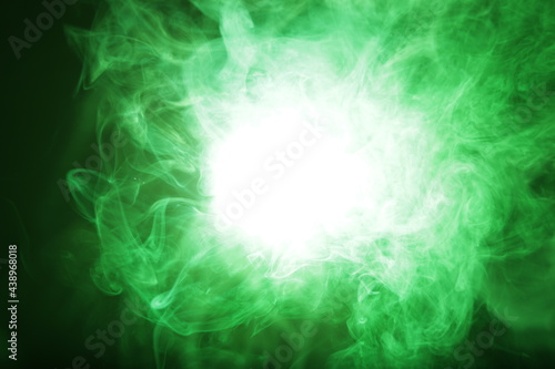 Artificial magic smoke in green light on black background
