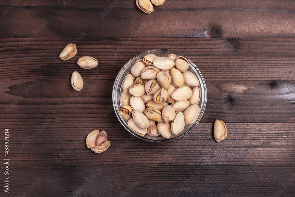 Pistachios in a bowl on a wooden table. Salted pistachios for beer. View from above Pistachios in a bowl on a wooden table. Salted pistachios for beer. View from above