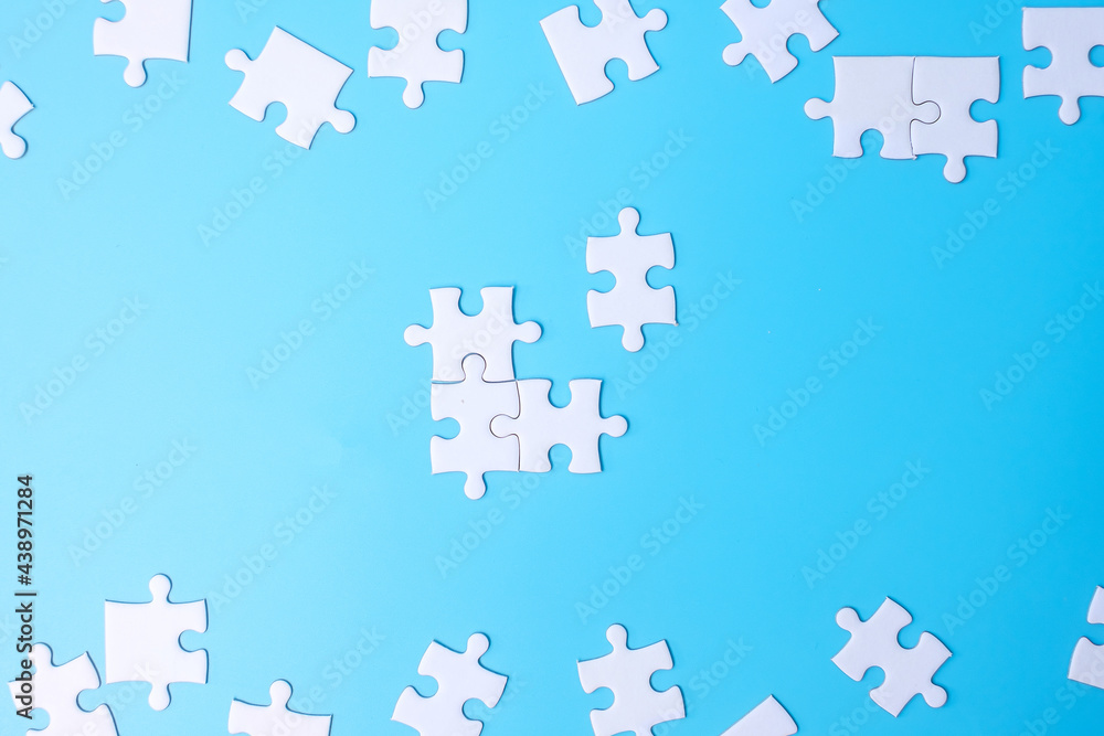 Naklejka premium Group of white puzzle jigsaw pieces on blue background. Concept of solutions, mission, success, goals, cooperation, partnership, strategy and puzzle day