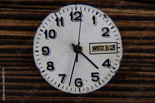 The clock face of a vintage watch on a wooden table.