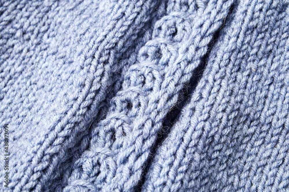 blue knitted product on knitting needles on a white background blue knitted product on knitting needles on a white background