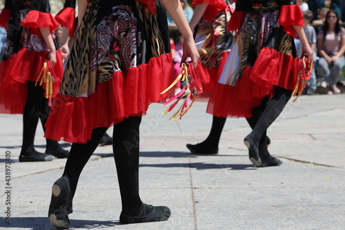 A female musical group in a beautiful colorful dress and in dance shoes dances with a tambourine in hand at a street festival in front of the audience.Close-up image.Background