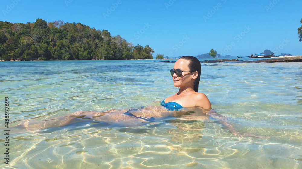 Young woman lying on the beach. Fashion model posing on a tropical island in sunglasses.