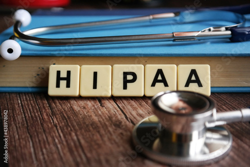 Wooden block written with HIPAA ( Health Insurance Portability and Accountability Act ) inscription with stethoscope, magnify glasses and flower.