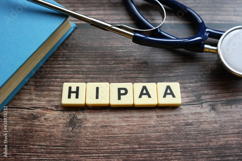 Wooden block written with HIPAA ( Health Insurance Portability and Accountability Act ) inscription with stethoscope, magnify glasses and flower.