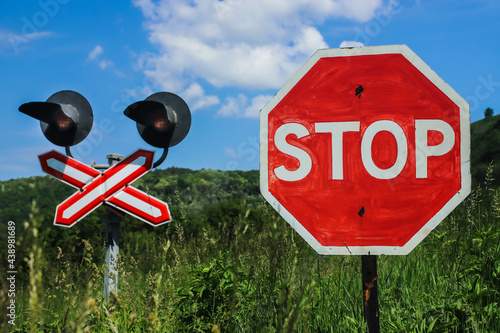 stop sign in front of a railway crossing on a background of blue sky with clouds photo