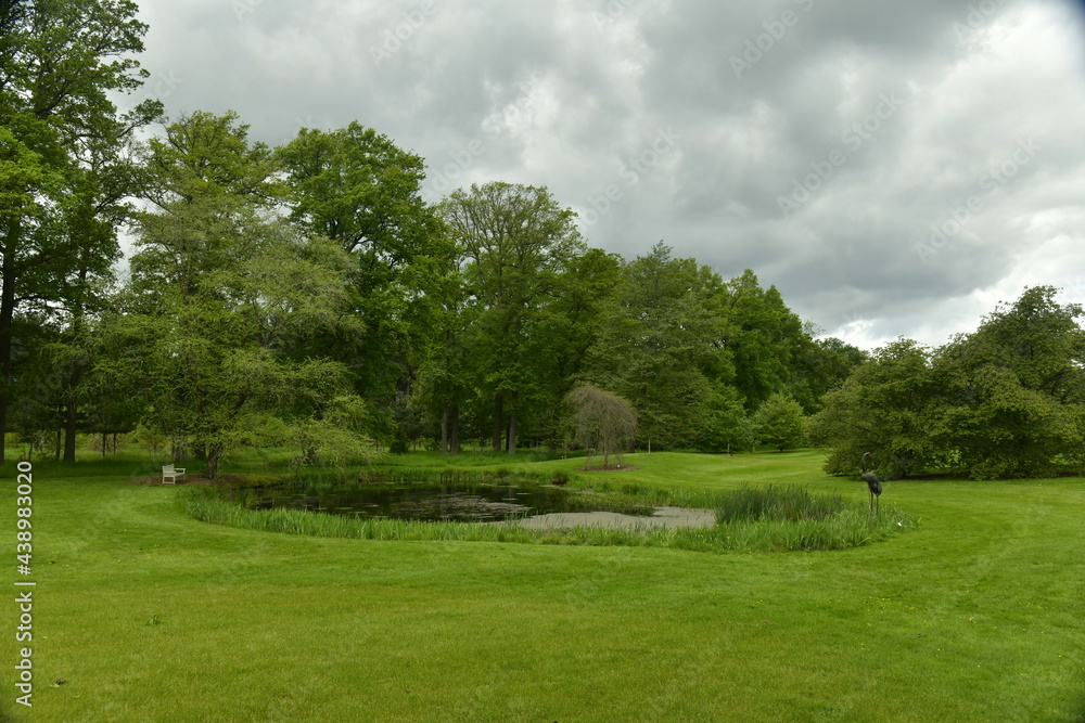 L'étang biologique et l'héron métallique sous l'ombre d'un nuage menaçant à l'arboretum de Wespelaar en Brabant Flamand
